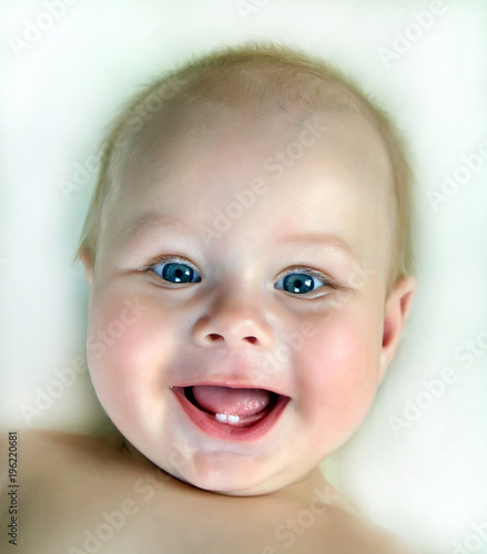 Close up of adorable 6 months old baby with first teeth laughing  looking at camera
