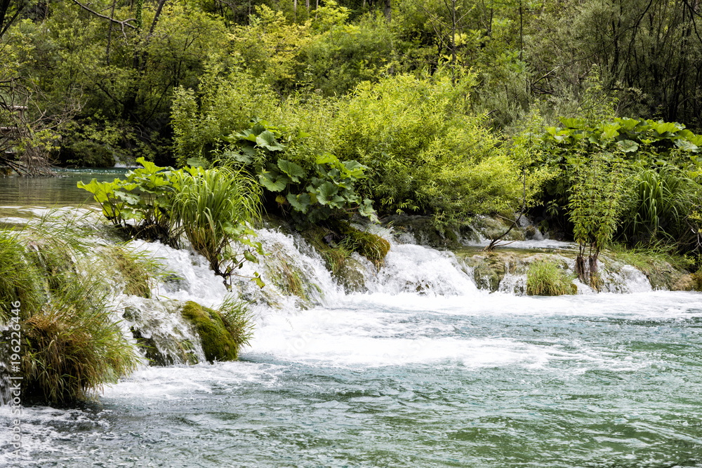 Paradise landscape with waterfall flowing into a pond in Plitvice Lakes National Park in summer in Croatia Paradise landscape with waterfall flowing into a pond in Plitvice Lakes National Park in summer in Croatia