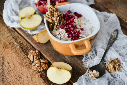 Breakfast: granola with pomegranate and walnuts and green Apple on natural wooden background rustic. The concept of healthy and high-carbon nutrition.