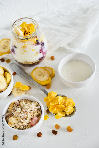 Breakfast in a jar: cornflakes, banana, fresh berries, granola, yogurt on a light background. The concept of healthy eating, high-carbon Breakfast.