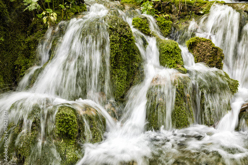 Small waterfall flows over moss-covered stones in Plitvice Lakes National Park in summer in Croatia