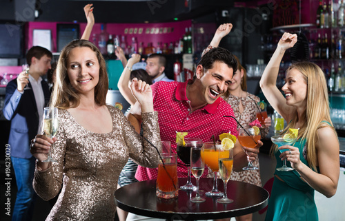 Portrait of smiling females and males having fun in the bar