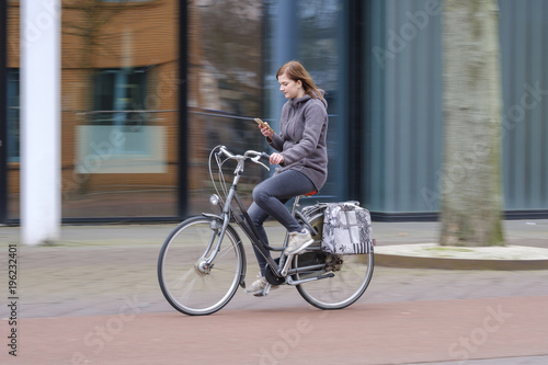 girl riding a bike and looks at her smartphone, danger