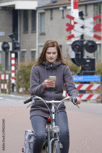 girl riding a bike and looks at her smartphone, danger