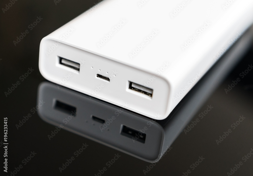 White power bank on mirrored surface. Space for your text. White power bank on mirrored surface. Space for your text.