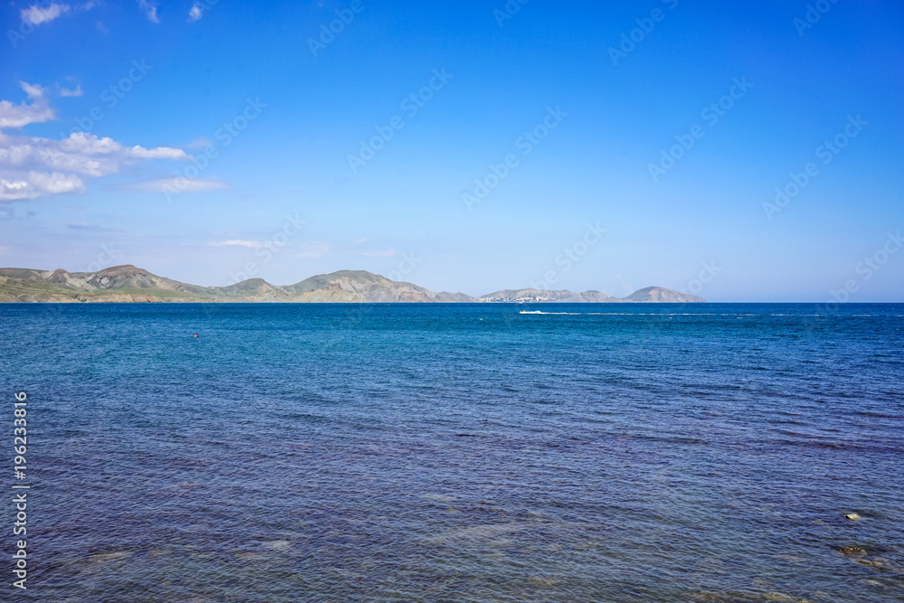 Seascape with a view of the coastline and the calm blue sea.