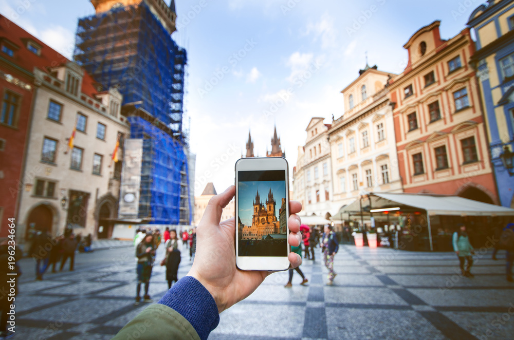 Fototapeta premium Photo camera of smartphone and old Prague centre with famous sightseeing. Old city square with people during the sunset