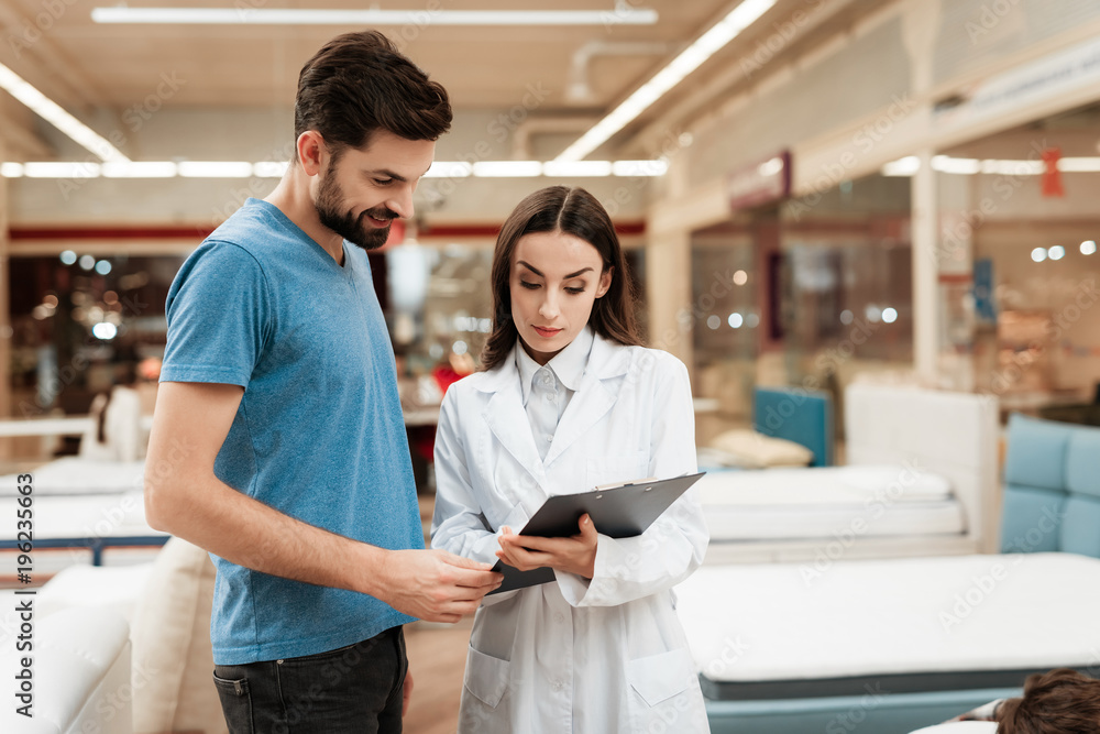 Lovely woman consultant with confident man make out purchase of mattress in store. Lovely woman consultant with confident man make out purchase of mattress in store.