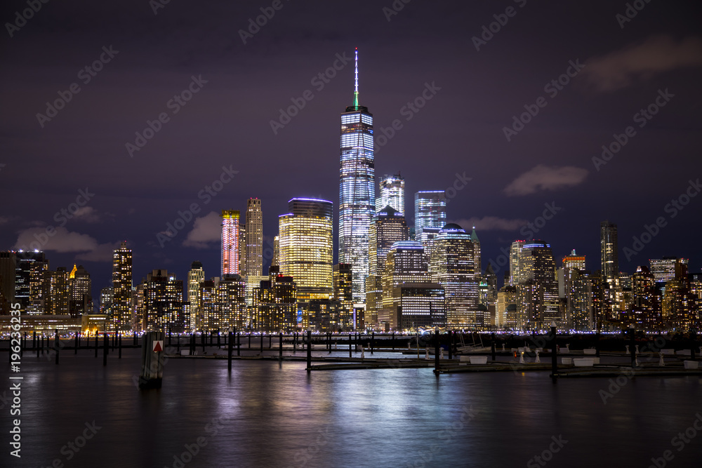 The lights of Lower Manhattan and the World Trade Center reflect off the water of the Hudson River, as seen from Hoboken, New Jersey.