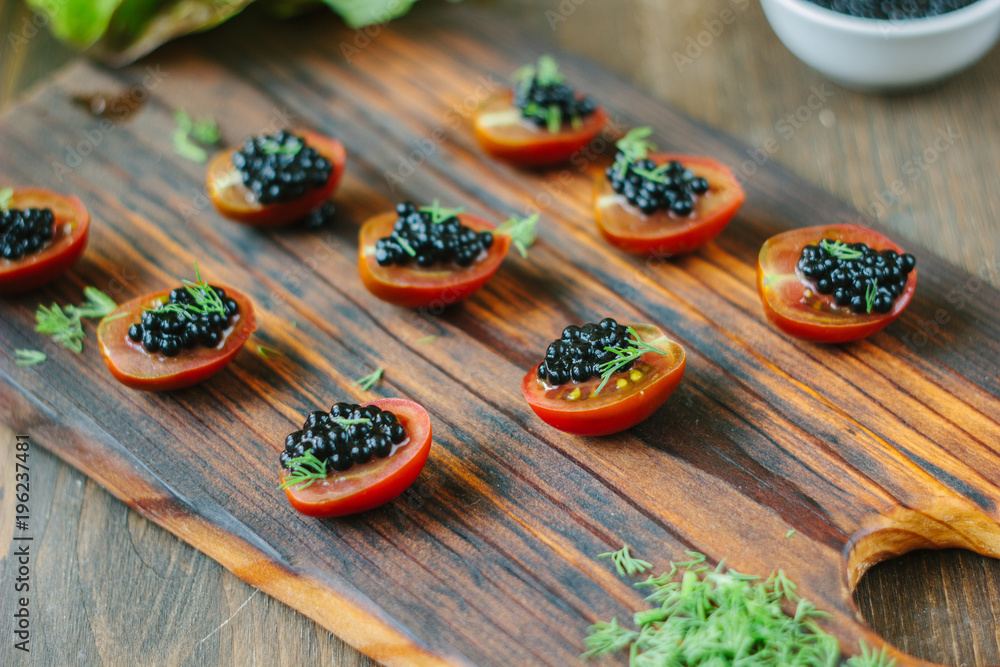 Small appetizers with cherry tomatoes and black caviar. Small appetizers with cherry tomatoes and black caviar.