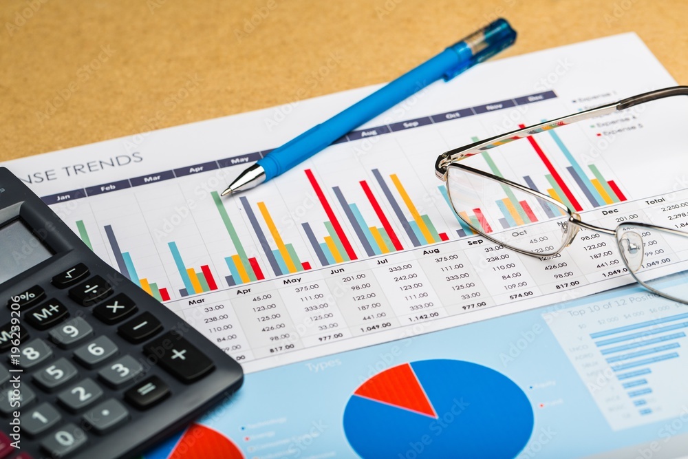 Pen, Eyeglasses and Calculator on Business Graphs and Charts Pen, Eyeglasses and Calculator on Business Graphs and Charts