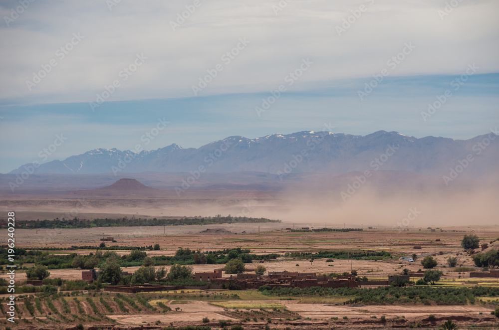 Sandstorm in valley near of High Atlas mountain range. With snow on the peaks at background. Morocco