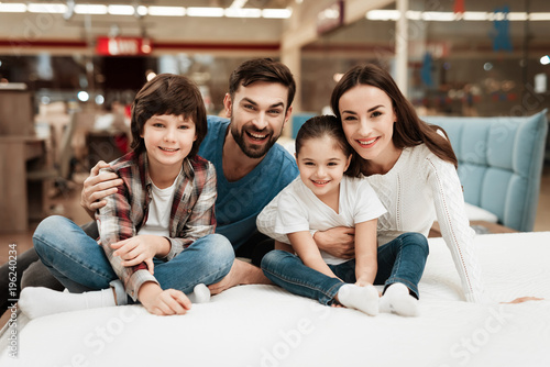 Big happy family chooses soft mattress in orthopedic furniture store. Healthy posture concept.