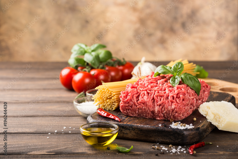 Ingredients for spaghetti Bolognaise or Bolognese with savory minced beef and tomato, basil and spices. Italian healthy food concept with copy space. Ingredients for spaghetti Bolognaise or Bolognese with savory minced beef and tomato, basil and spices. Italian healthy food concept with copy space.