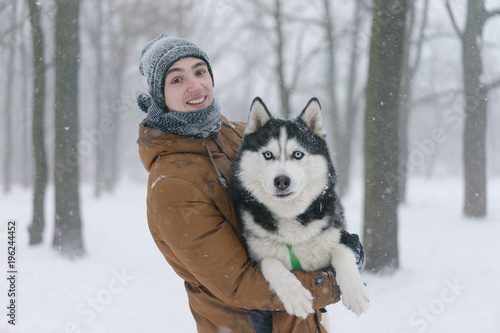 Man walking with dog winter time with snow in forest and siberian husky dog friendship © Tetiana
