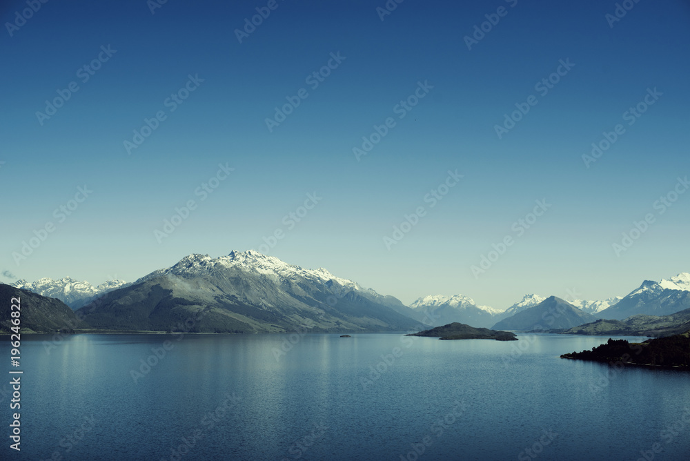 Paisaje de montañas con picos nevados. Las montañas se reflejan en un lago. Escena diurna, cielo azul y despejado. Nueva Zelanda.