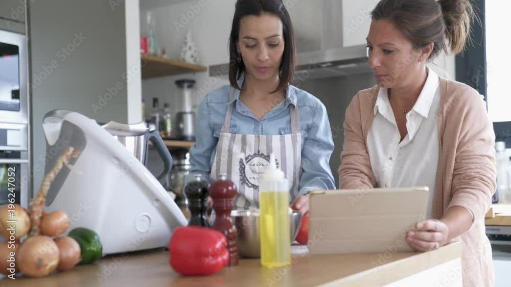 Friends cooking together with kitchen robot and tablet Friends cooking together with kitchen robot and tablet