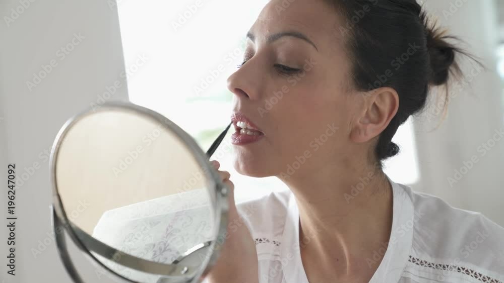 Beautiful woman applying lipstick on in front of mirror Beautiful woman applying lipstick on in front of mirror