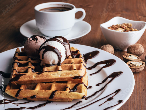 Fresh waffles with ice cream and maple syrup  on a wooden background