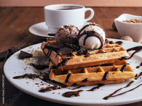 Fresh waffles with ice cream and maple syrup  on a wooden background