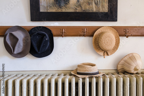 Wall hanger with various hats on it, radiator and old painting