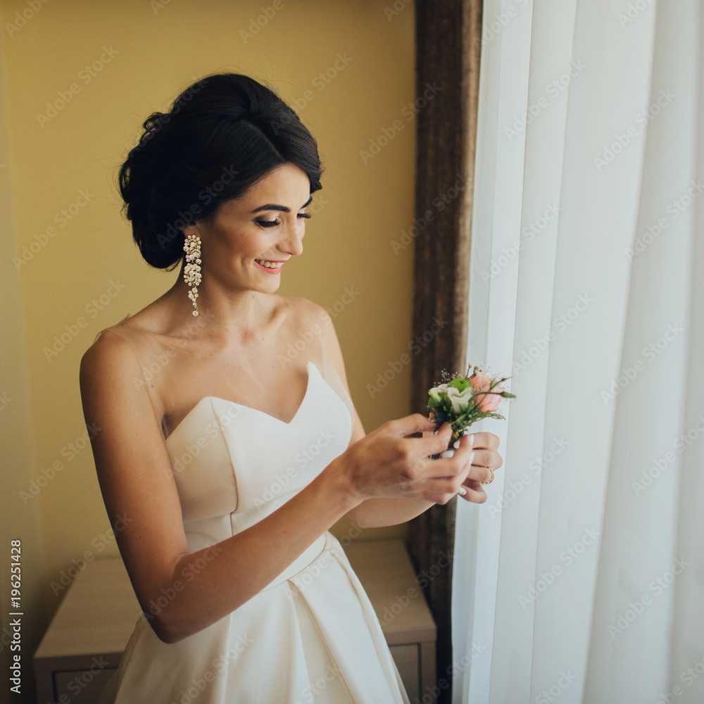Bride holds little white boutonniere in her arms Bride holds little white boutonniere in her arms