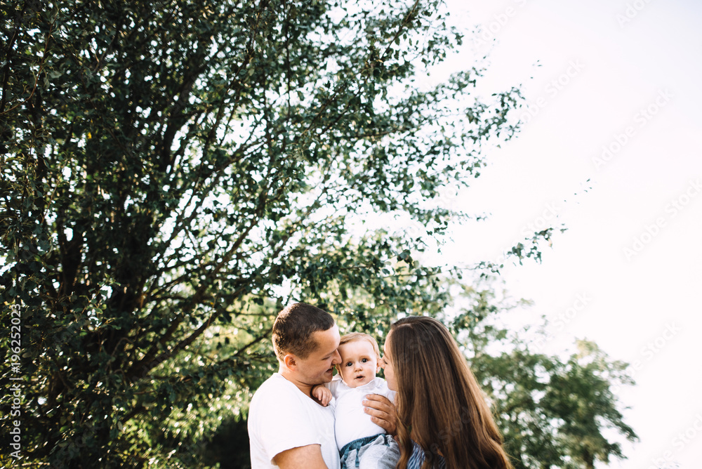 Amazing photo of a beautiful and happy family. Daddy, Mom and their little cute son, they're all smiling Amazing photo of a beautiful and happy family. Daddy, Mom and their little cute son, they're all smiling