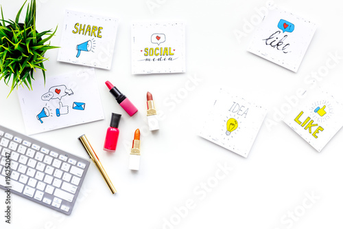 Beauty blogger workplace concept. Keyboard, cosmetics, social media icons on white desk top view space for text