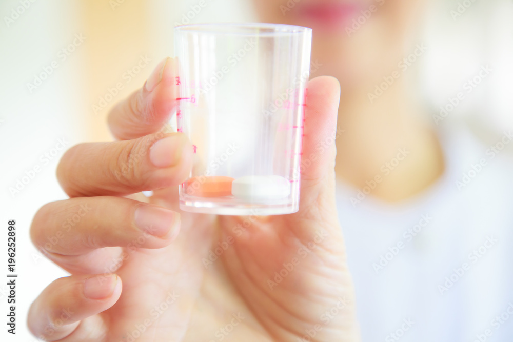 female nurse or doctor in white gown uniform holding pills in medical cup. Healthcare, medicine and professional specialist in medical services concept female nurse or doctor in white gown uniform holding pills in medical cup. Healthcare, medicine and professional specialist in medical services concept