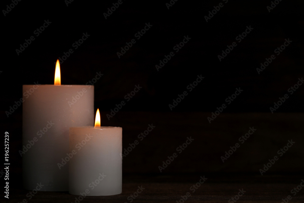 White burning candles on black background White burning candles on black background