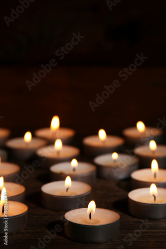 White burning candles on dark background