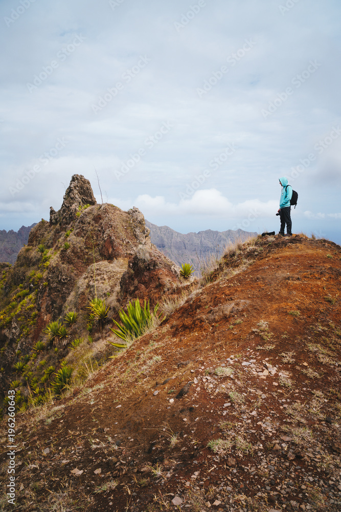 Traveler with backpack looking over the mountain peaks. Stunning arid landscape of Santo Antao island, Cabo Verde