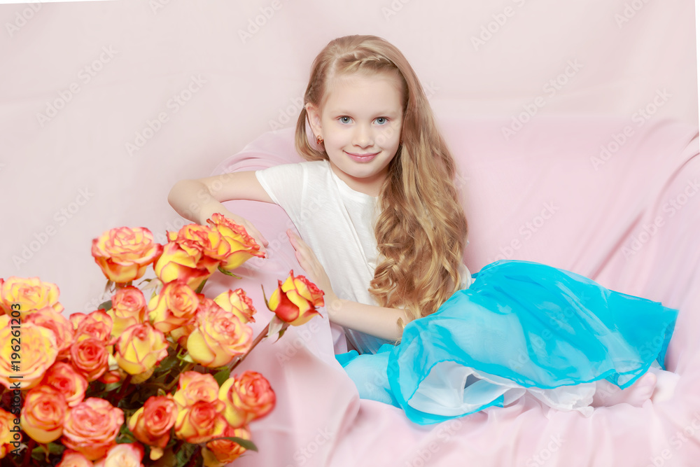 A beautiful little girl with long, light, curly hair, in a blue A beautiful little girl with long, light, curly hair, in a blue