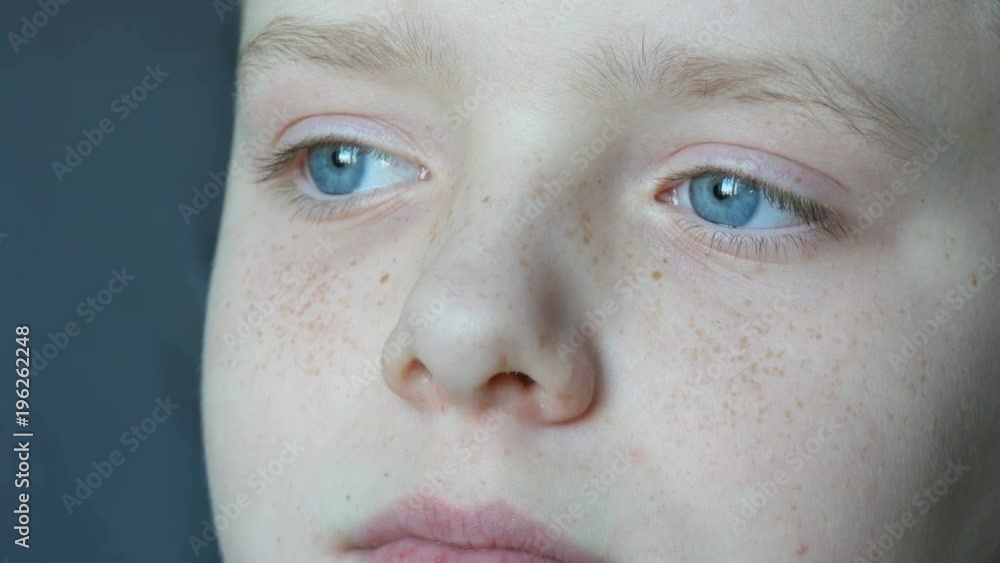 Face of a boy teenager with freckles close-up view. A boy with blue eyes looking up Face of a boy teenager with freckles close-up view. A boy with blue eyes looking up