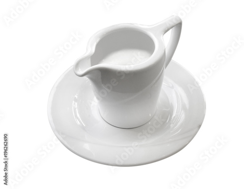 coffee creamer on a saucer on an empty white background. Mini pitcher full of milk 