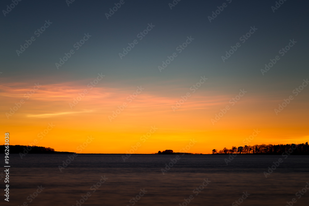 Fototapeta premium beautiful sunset at the sea with trees on the horizon