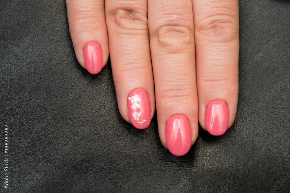 Nails covered with pink gel varnish with a sticker of white color with a flower pattern Nails covered with pink gel varnish with a sticker of white color with a flower pattern