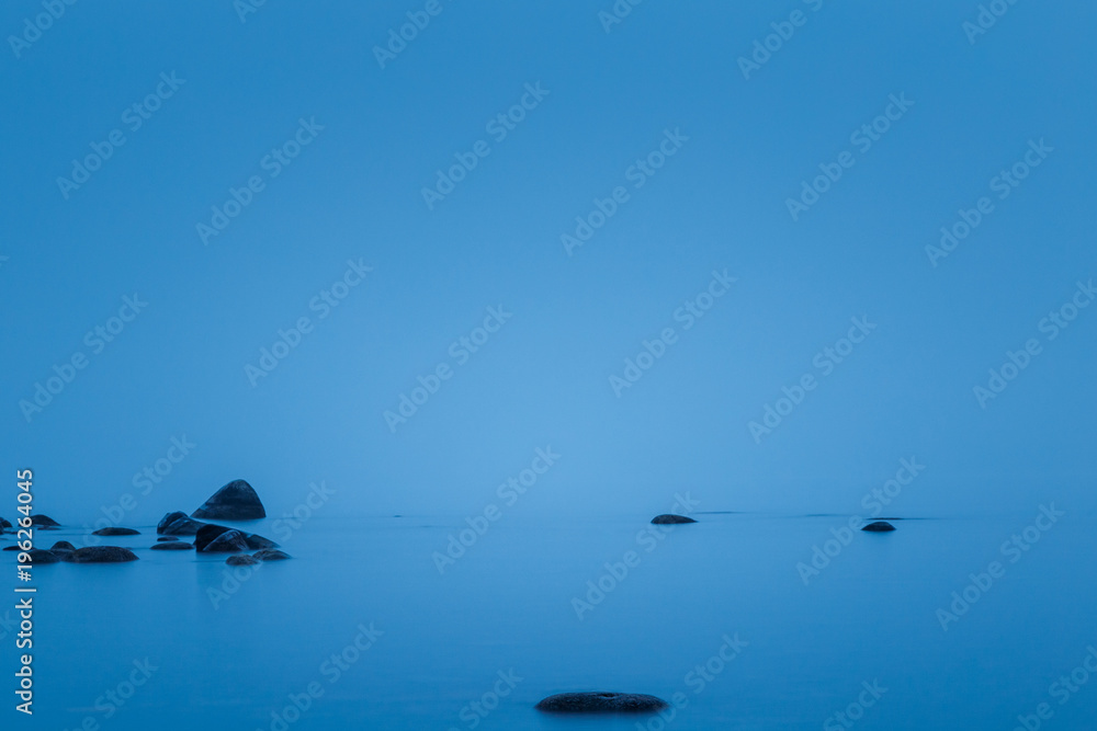 still lake with stones reflecting in the water and fog in the background
