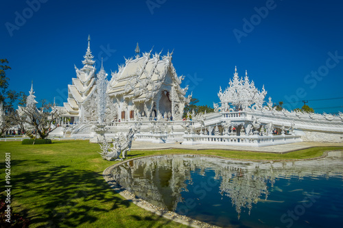 Beautiful outdoor view of white church of Wat Rong Khun temple in Chiangrai, Thailand, reflected in the water
