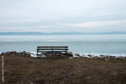lonely bench at the frozen lake - summer is far