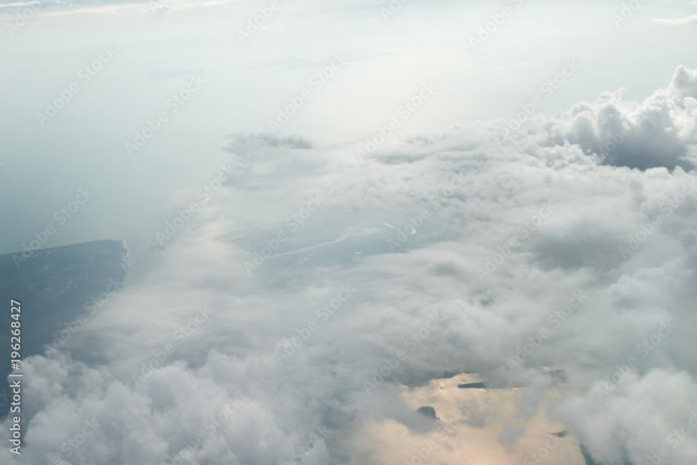 View from the airplane window to the clouds and the relief of the earth 