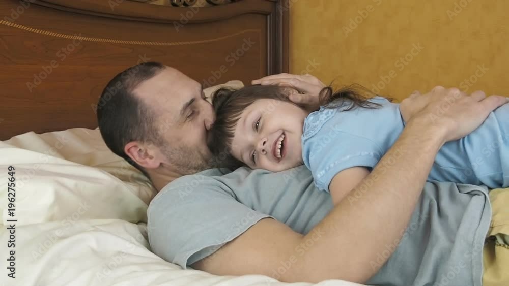Daddy's girl. The daughter is hugging her dad on the bed. Daddy's girl. The daughter is hugging her dad on the bed.