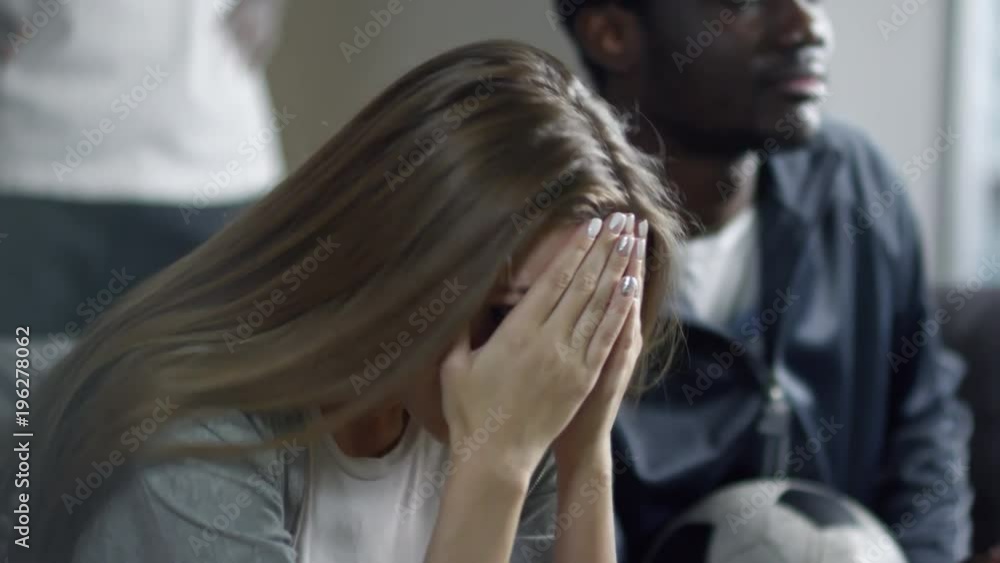 Closeup of young beautiful woman watching soccer game on TV and covering face with hands while getting sad about team failure Closeup of young beautiful woman watching soccer game on TV and covering face with hands while getting sad about team failure