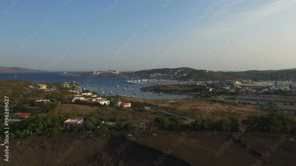 Flight through hill towards rural evening village landscape with small houses, dusty roads, dry arid grass, bushes, Aegean sea bay with yachts, fishing boats in water. Attica, Greece. Aerial. Flight through hill towards rural evening village landscape with small houses, dusty roads, dry arid grass, bushes, Aegean sea bay with yachts, fishing boats in water. Attica, Greece. Aerial.