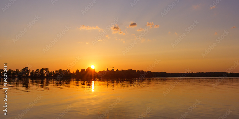 Sun over the church at sunset on Lake Seliger