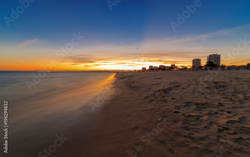 Sunset over the Algarve Beach Praia Alvor, in the background the city of Lagos