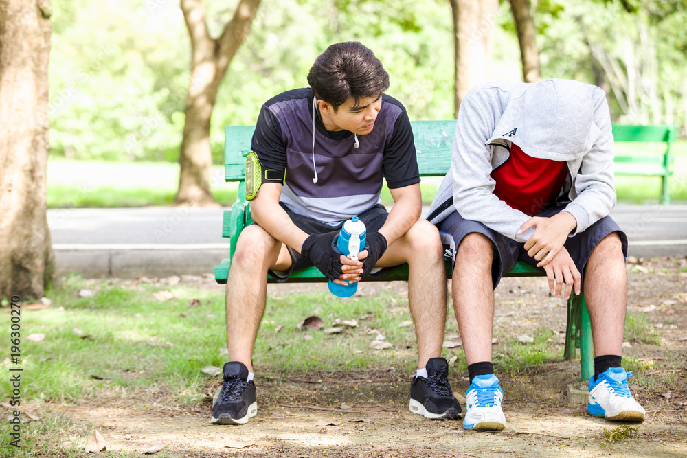 Asian sport men drinking water after running in park Asian sport men drinking water after running in park