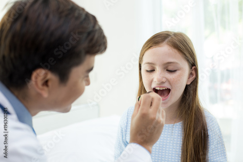 Male doctor examining girl mouth in clinic. People with health care and medical concept