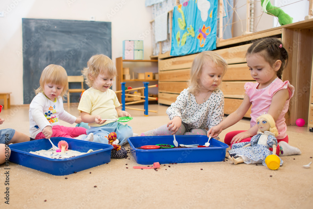 Group of children playing in kindergarten or daycare centre - obrazy, fototapety, plakaty 