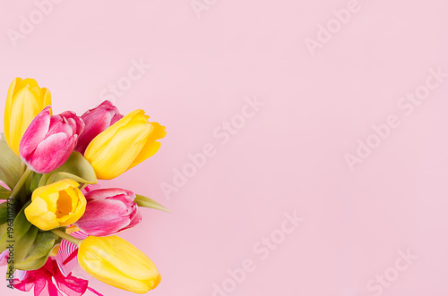 Fototapeta Naklejka Na Ścianę i Meble -  Fresh bouquet of yellow and red tulips on soft pastel pink background with copy space. April easter spring background.